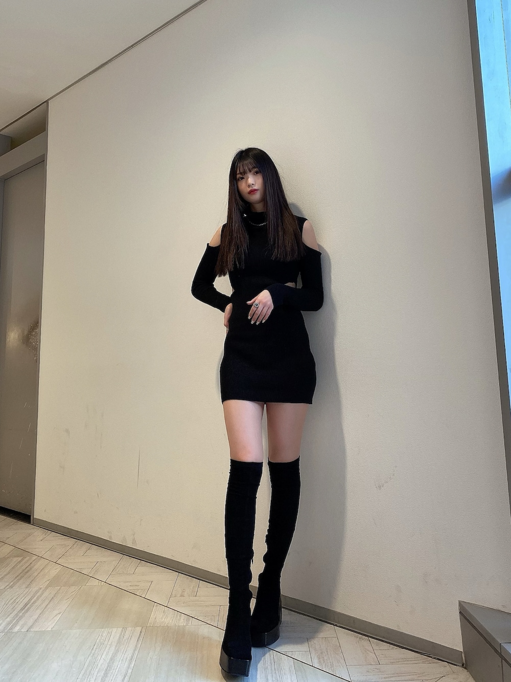 ブラック系のワンピース、ブラック系のブーツ、シルバー系のアクセサリーを着用したレディースの冬コーディネートの2枚目の写真