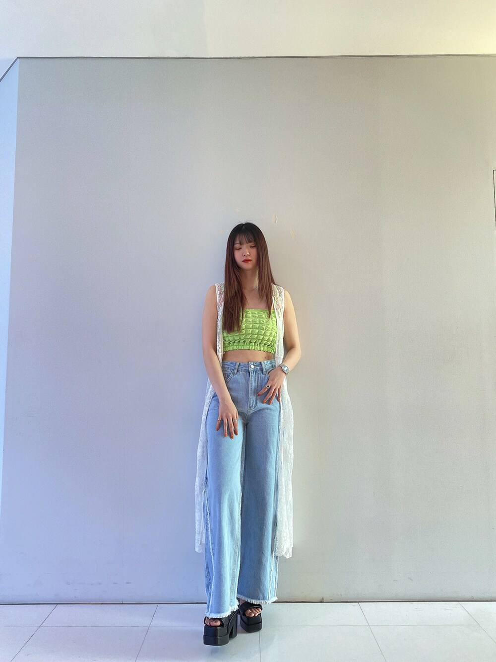 グリーン系のキャミソール、ホワイト系のカーディガン/ボレロ、ブルー系のデニムパンツを着用したレディースの春コーディネートの2枚目の写真