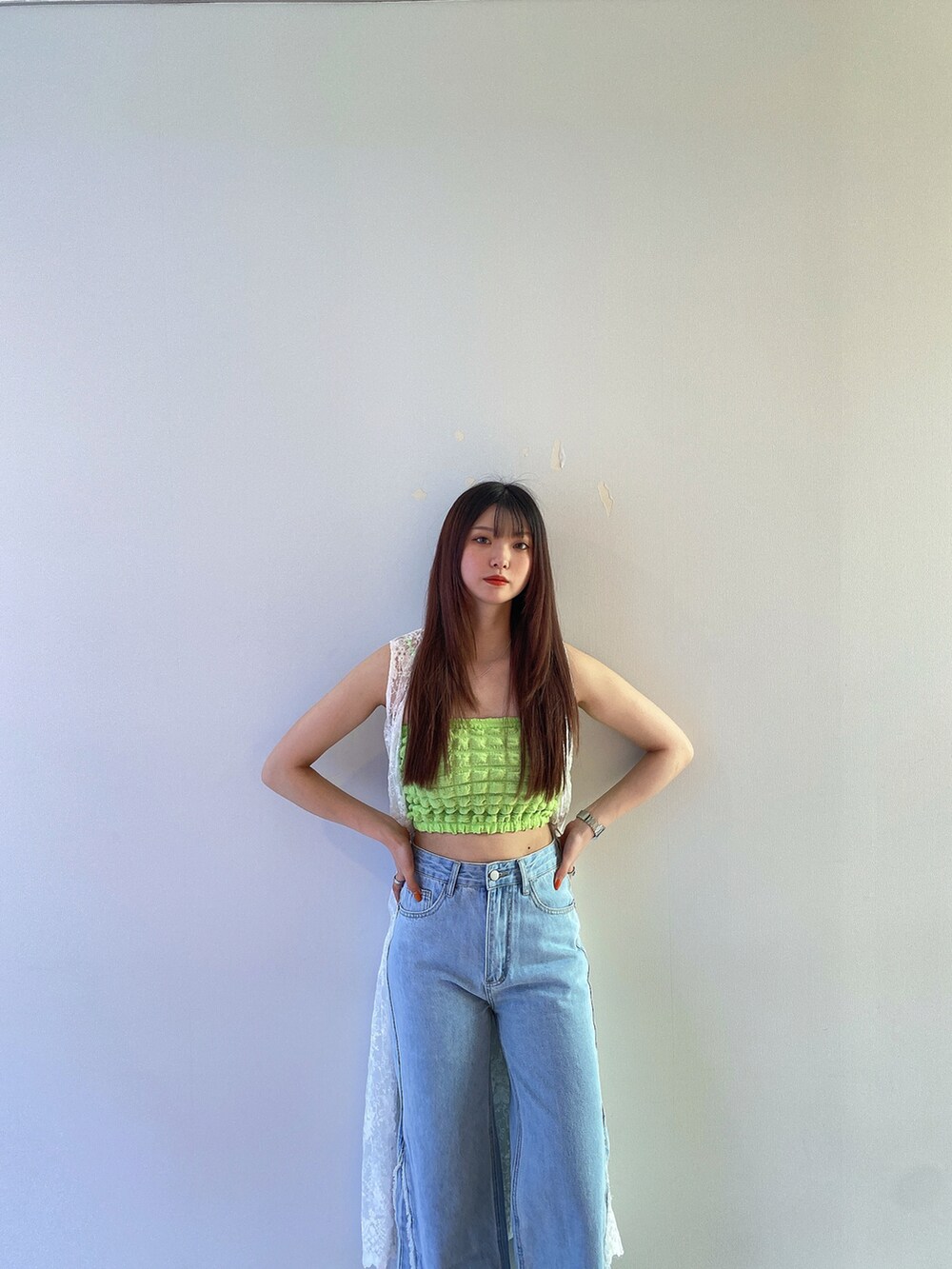 グリーン系のキャミソール、ホワイト系のカーディガン/ボレロ、ブルー系のデニムパンツを着用したレディースの春コーディネートの4枚目の写真