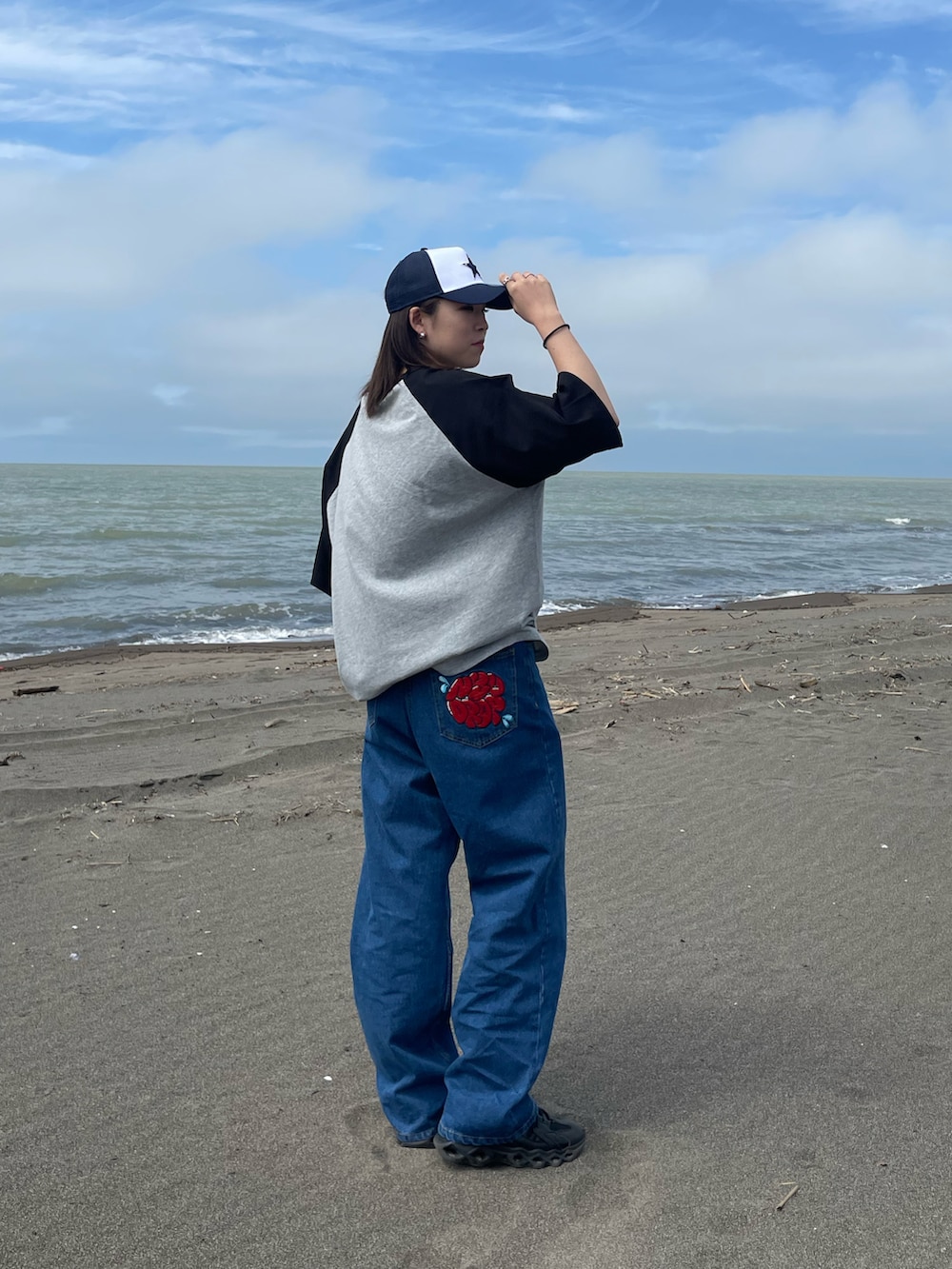 グレー系のTシャツ/カットソー、ブルー系のデニムパンツ、ブラック系のスニーカーを着用したレディースの春コーディネートの2枚目の写真