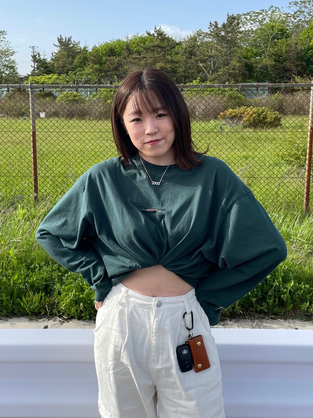 ホワイト系のパンツ、グリーン系のスニーカー、グリーン系のTシャツ/カットソーを着用したレディースの春コーディネートの2枚目の写真