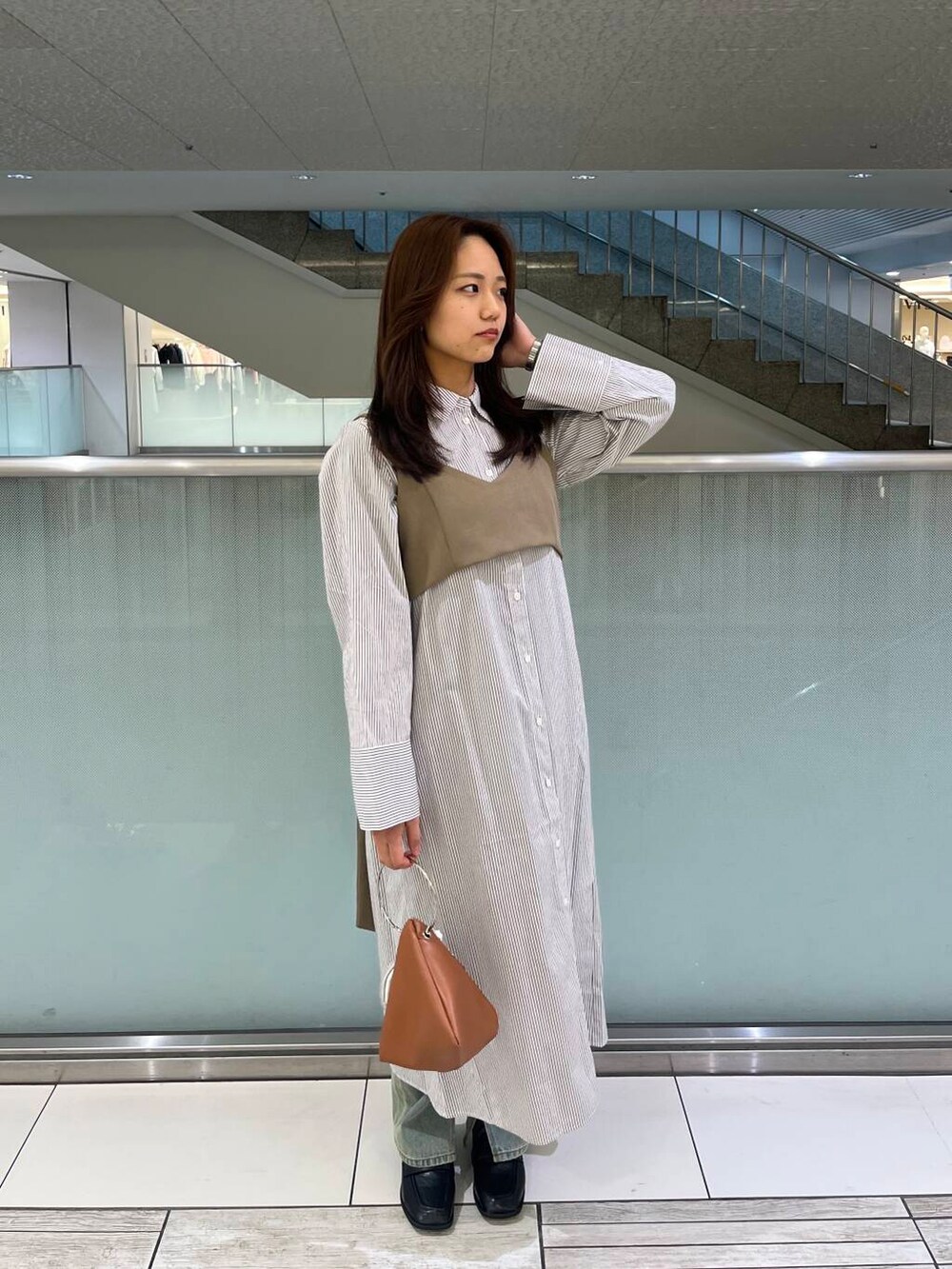 ブルー系のデニムパンツ、ブラック系のローファー、イエロー系のハンドバッグを着用したレディースの冬コーディネートの2枚目の写真