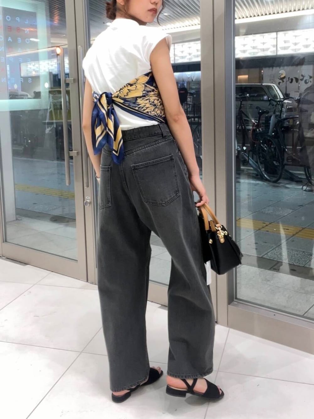 ブラック系のトートバッグ、グレー系のデニムパンツ、ホワイト系のTシャツ/カットソーを着用したレディースの夏コーディネートの3枚目の写真