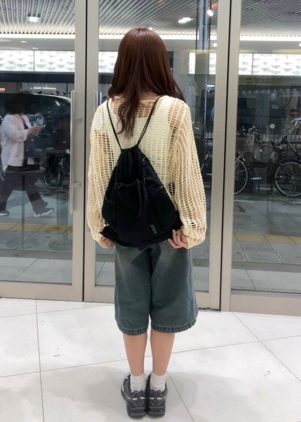 グレー系のスニーカー、ホワイト系のタンクトップ、ブラック系のショルダーバッグを着用したレディースの春コーディネートの3枚目の写真