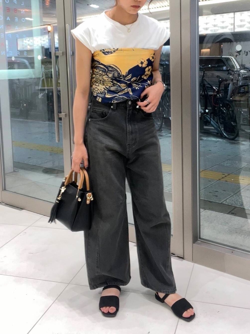 ブラック系のトートバッグ、グレー系のデニムパンツ、ホワイト系のTシャツ/カットソーを着用したレディースの夏コーディネートの2枚目の写真