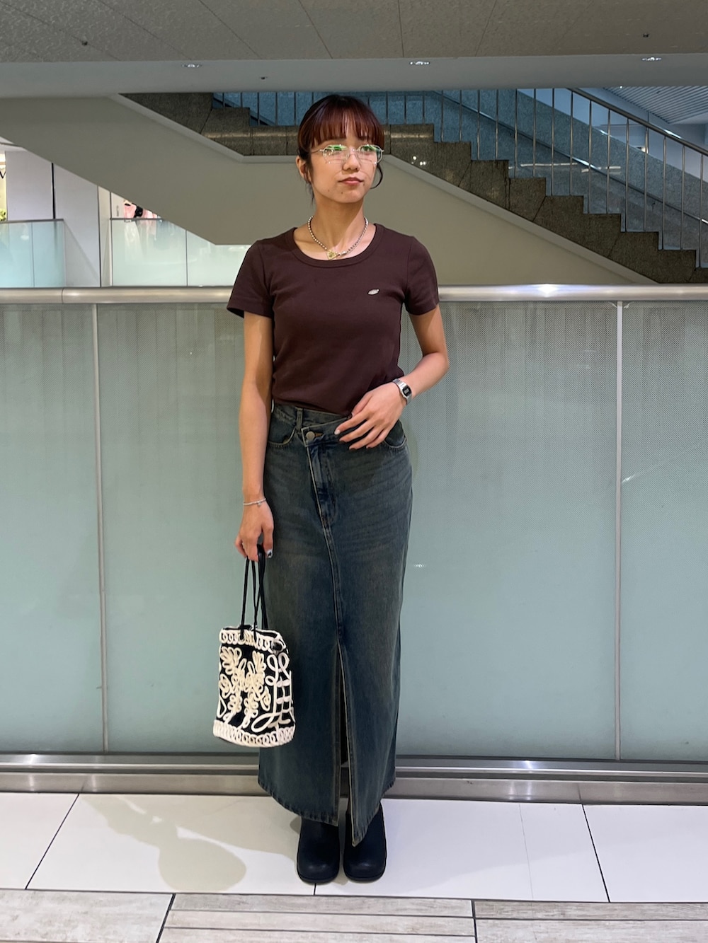 ブラウン系のTシャツ/カットソー、ブルー系のスカート、ブラック系のハンドバッグを着用したレディースの夏コーディネートの2枚目の写真