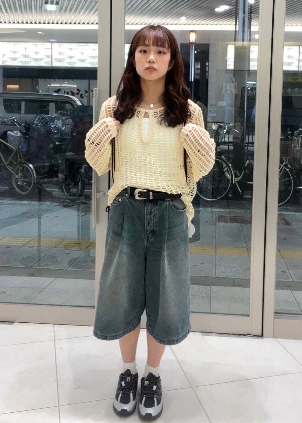 グレー系のスニーカー、ホワイト系のタンクトップ、ブラック系のショルダーバッグを着用したレディースの春コーディネートの2枚目の写真