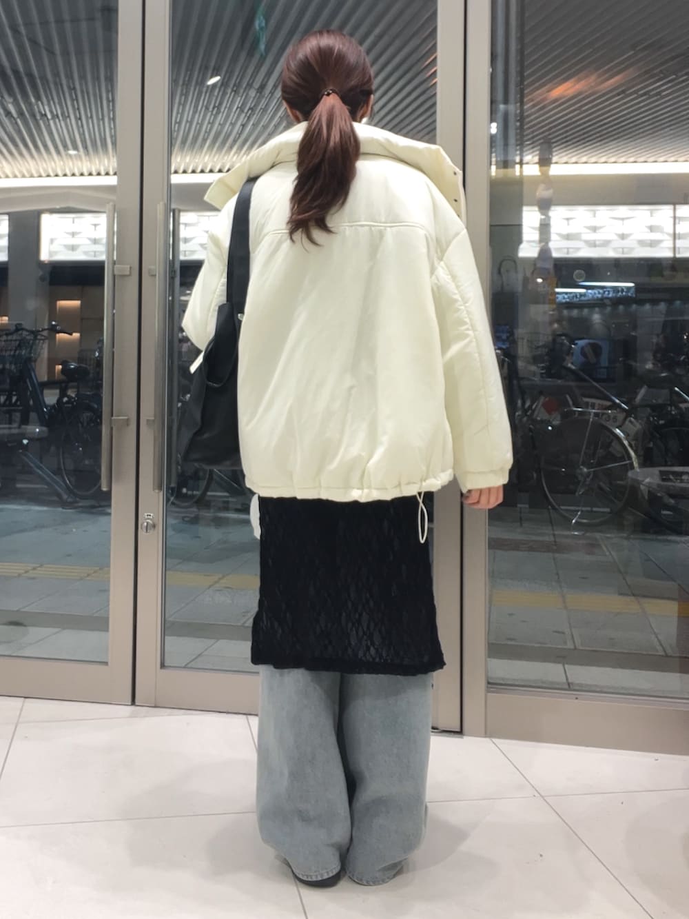 グレー系のニット/セーター、ブラック系のワンピース、ブルー系のデニムパンツを着用したレディースの秋コーディネートの4枚目の写真