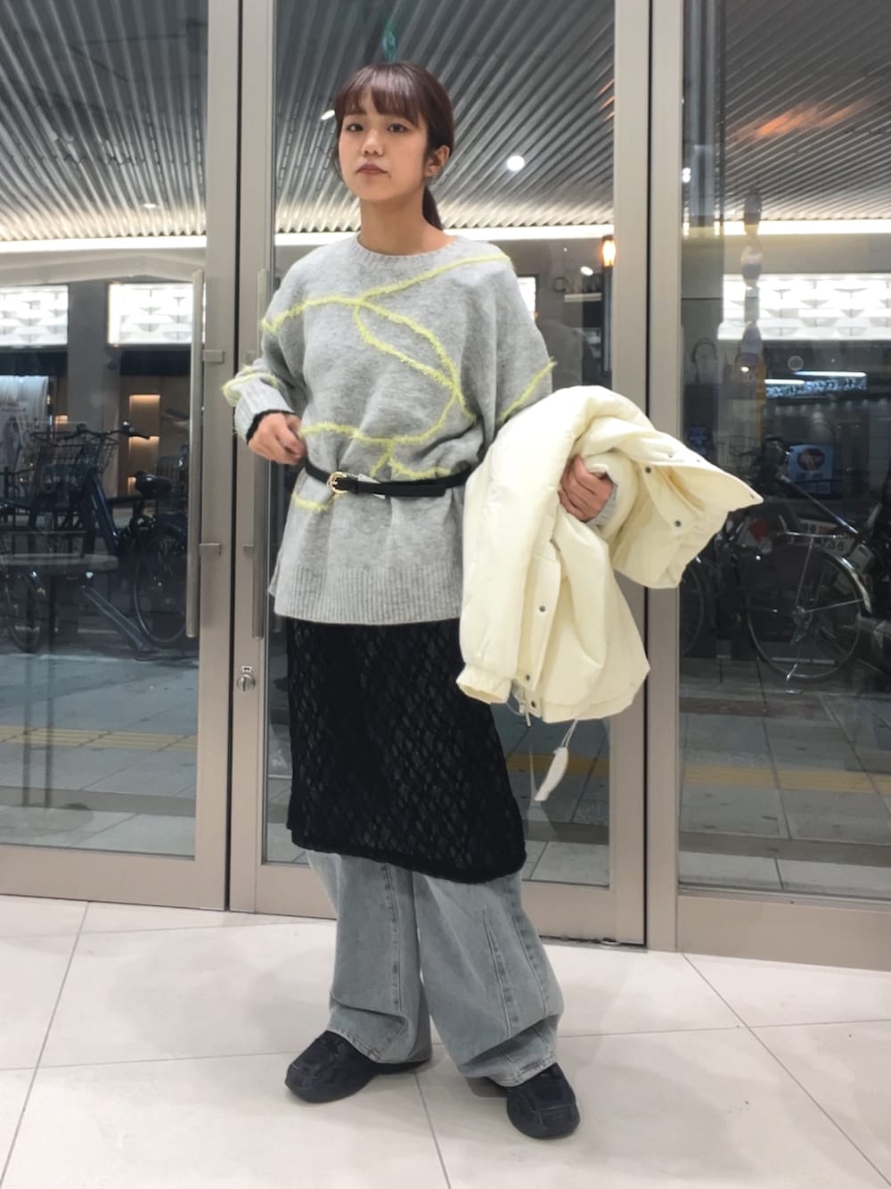 グレー系のニット/セーター、ブラック系のワンピース、ブルー系のデニムパンツを着用したレディースの秋コーディネートの2枚目の写真