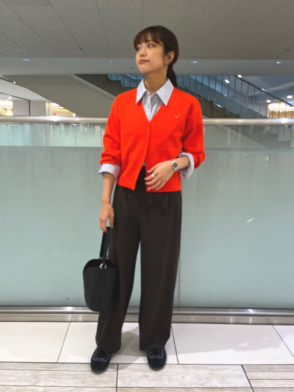 レッド系のカーディガン/ボレロ、ブラウン系のその他パンツ、ブラック系のハンドバッグを着用したレディースの秋コーディネートの2枚目の写真