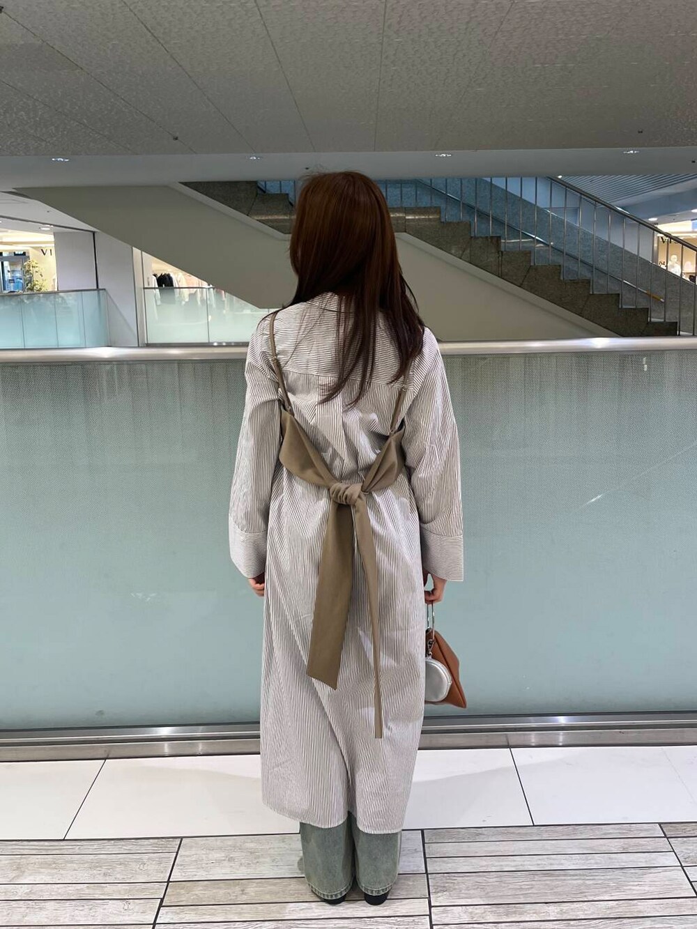 ブルー系のデニムパンツ、ブラック系のローファー、イエロー系のハンドバッグを着用したレディースの冬コーディネートの3枚目の写真