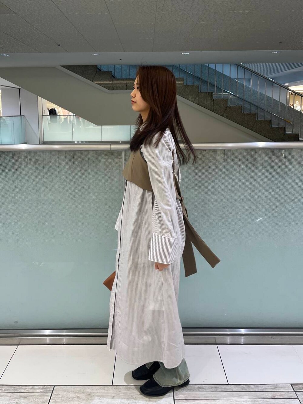 ブルー系のデニムパンツ、ブラック系のローファー、イエロー系のハンドバッグを着用したレディースの冬コーディネートの4枚目の写真