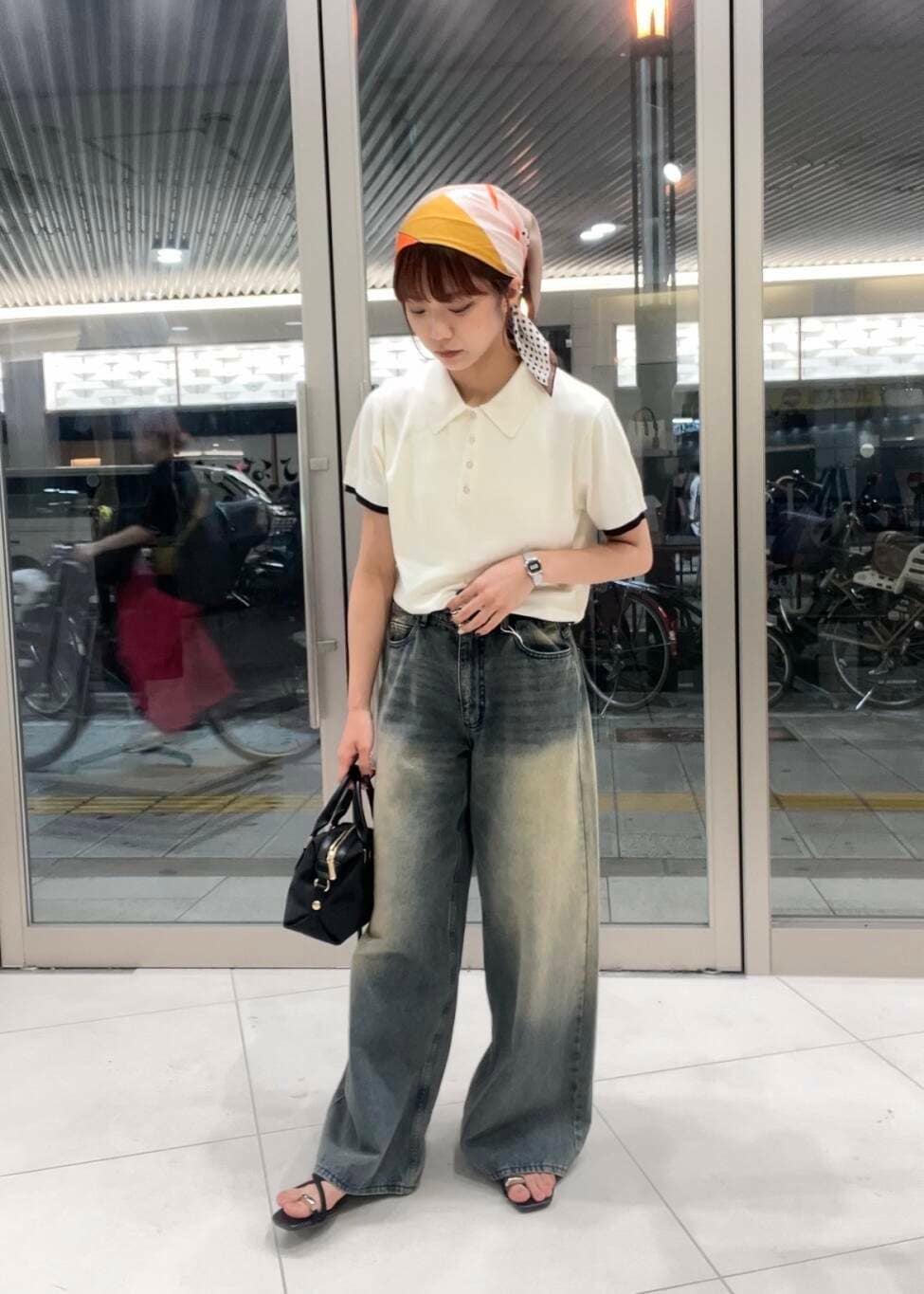 ブルー系のデニムパンツ、ブラック系のサンダル、ホワイト系のポロシャツを着用したレディースの夏コーディネートの2枚目の写真