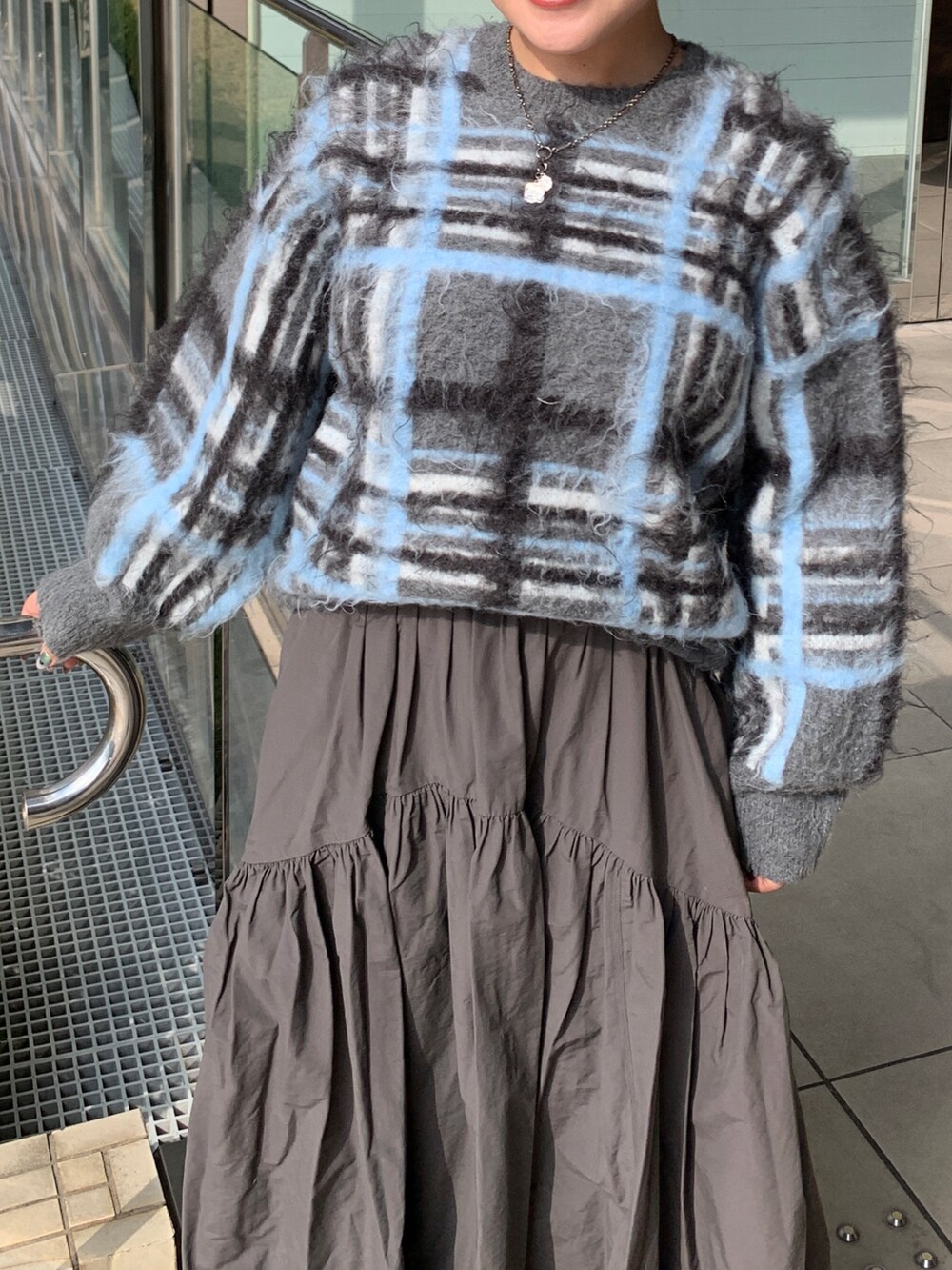 グレー系のニット/セーター、グレー系のスカートを着用したレディースの秋コーディネートの4枚目の写真