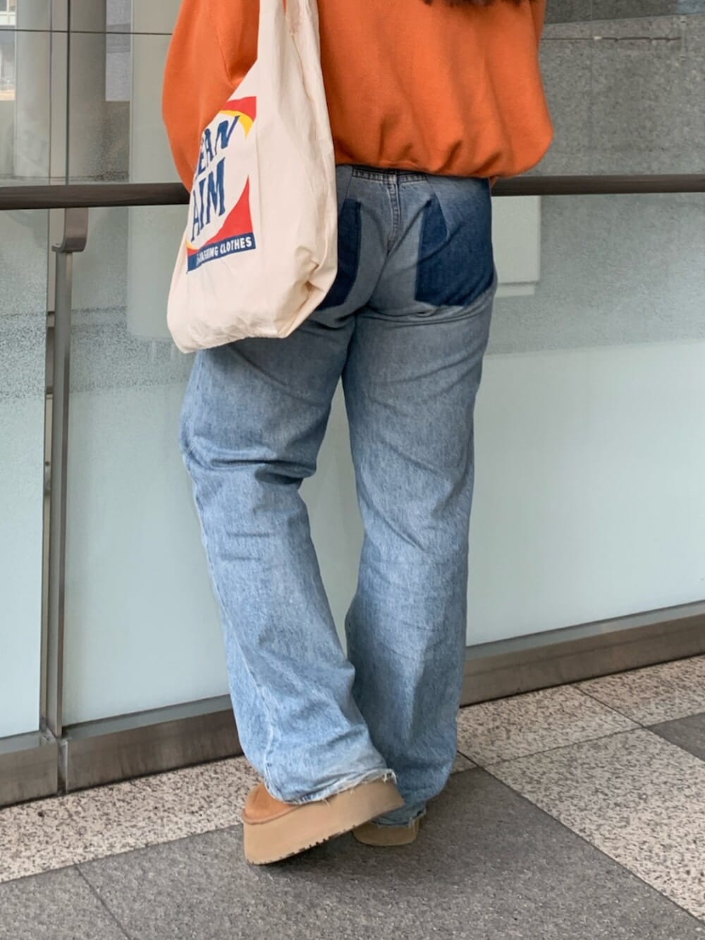 オレンジ系のニット/セーター、ブルー系のデニムパンツ、ホワイト系のトートバッグを着用したレディースの冬コーディネートの8枚目の写真