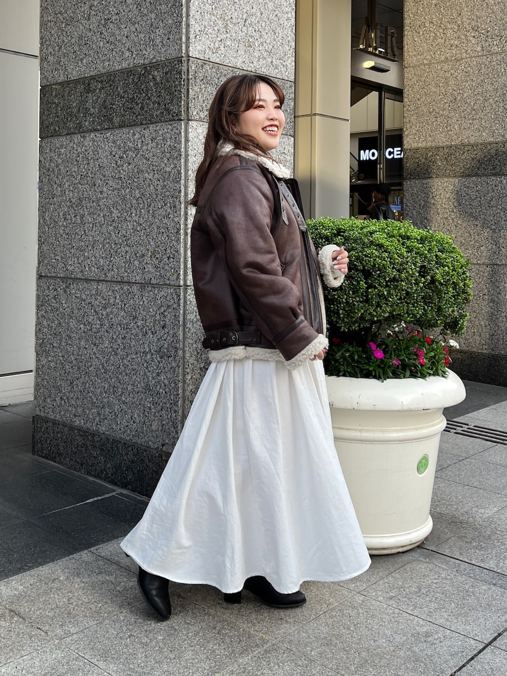 ブラウン系のムートンコート、ブラック系のワンピースを着用したレディースの秋コーディネートの2枚目の写真