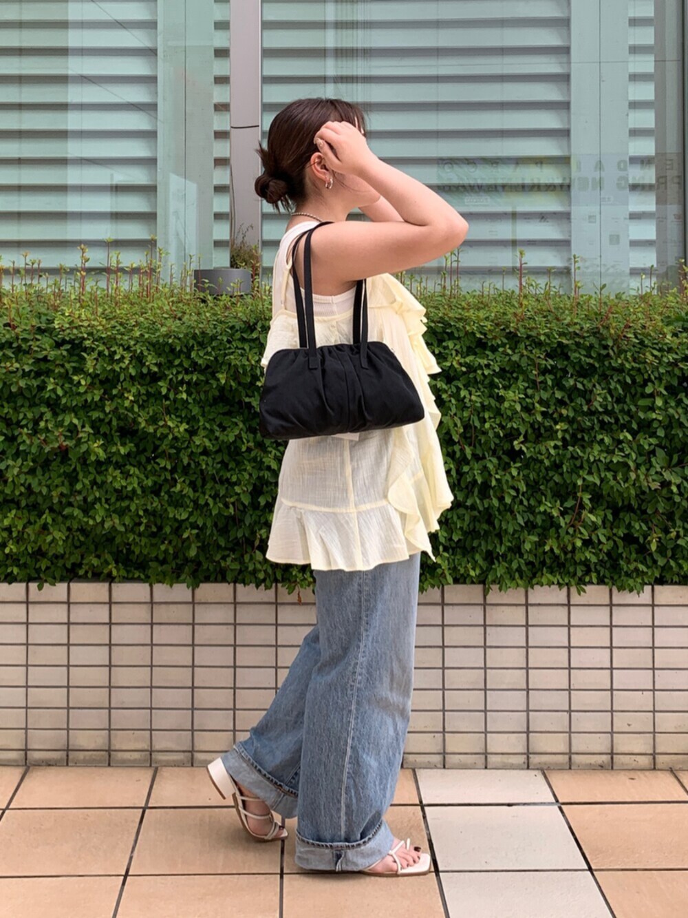 ブルー系のデニムパンツ、イエロー系のキャミソール、ホワイト系のタンクトップを着用したレディースの夏コーディネートの2枚目の写真