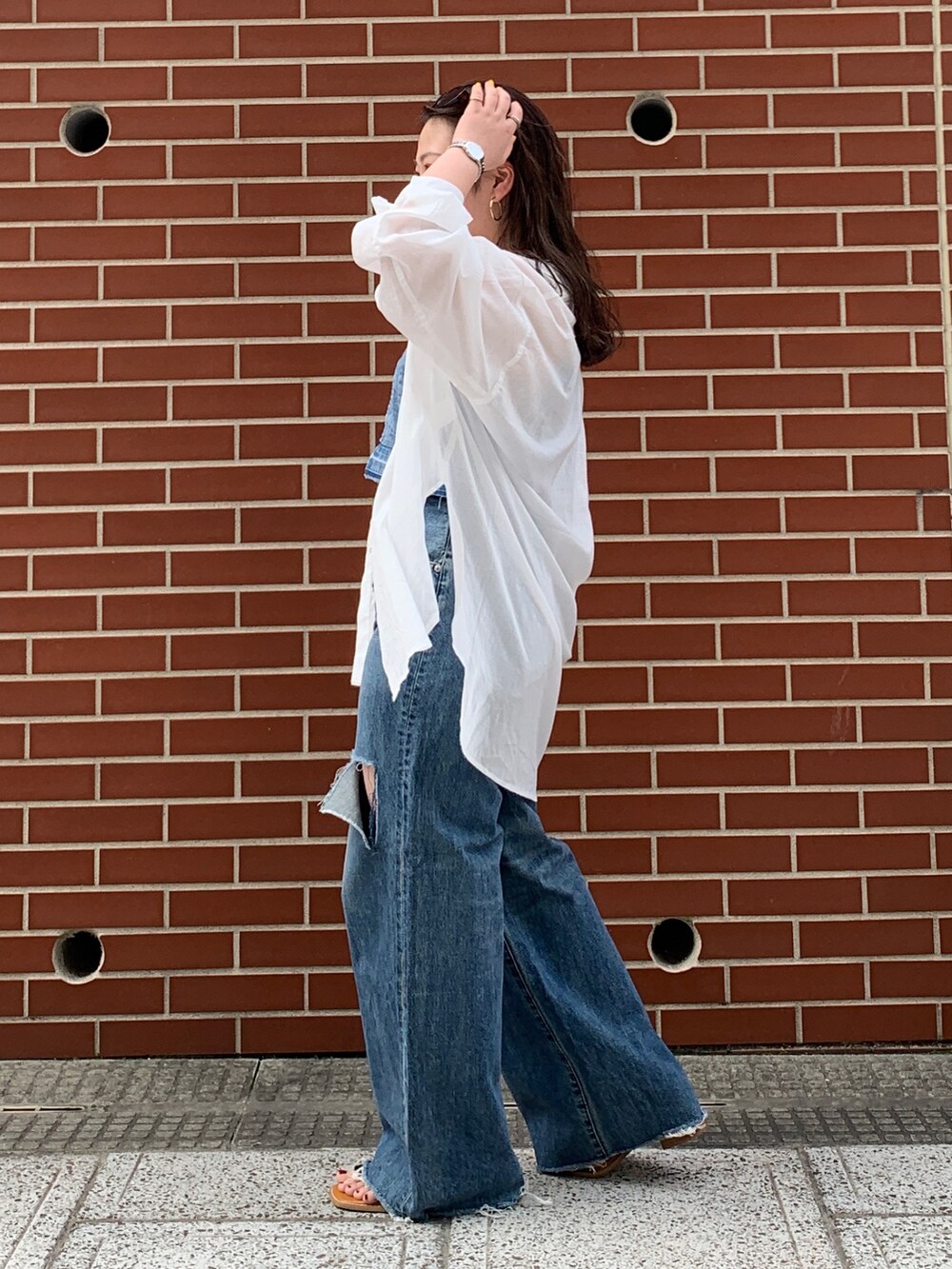 ブルー系のキャミソール、ホワイト系のシャツ/ブラウス、ブルー系のデニムパンツを着用したレディースの春コーディネートの2枚目の写真