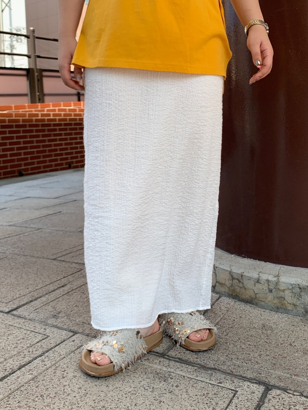 イエロー系のTシャツ/カットソー、ホワイト系のスカート、ホワイト系のキャミソールを着用したレディースの夏コーディネートの5枚目の写真