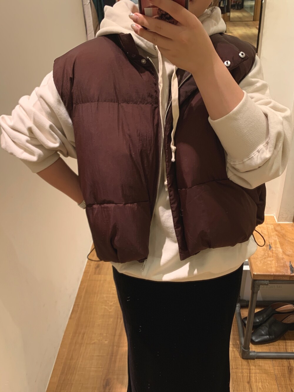 ブラウン系のダウンベスト、ホワイト系のパーカー、ブラック系のスカートを着用したレディースの秋コーディネートの4枚目の写真