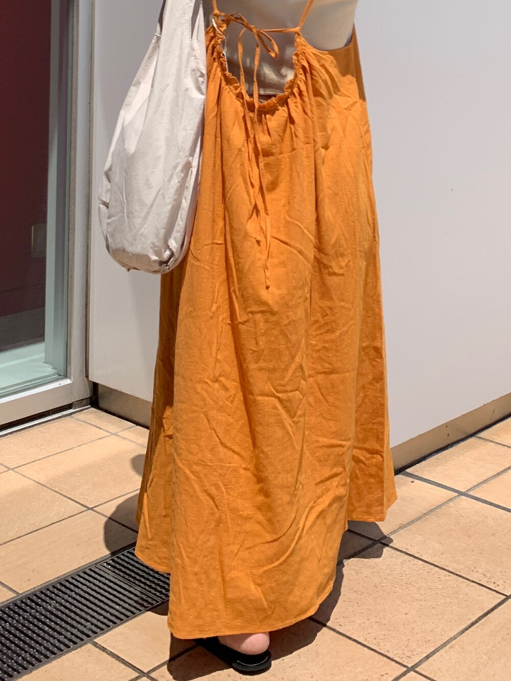 オレンジ系のワンピース、ホワイト系のハンドバッグを着用したレディースの夏コーディネートの7枚目の写真