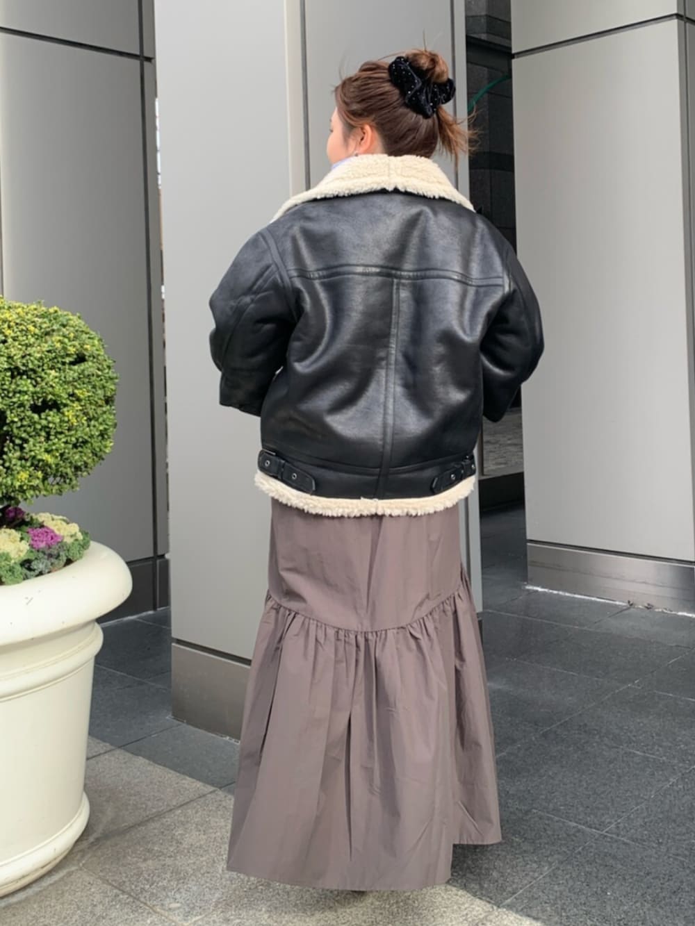 グレー系のスカート、ブラック系のブルゾン、ブルー系のニット/セーターを着用したレディースの冬コーディネートの3枚目の写真