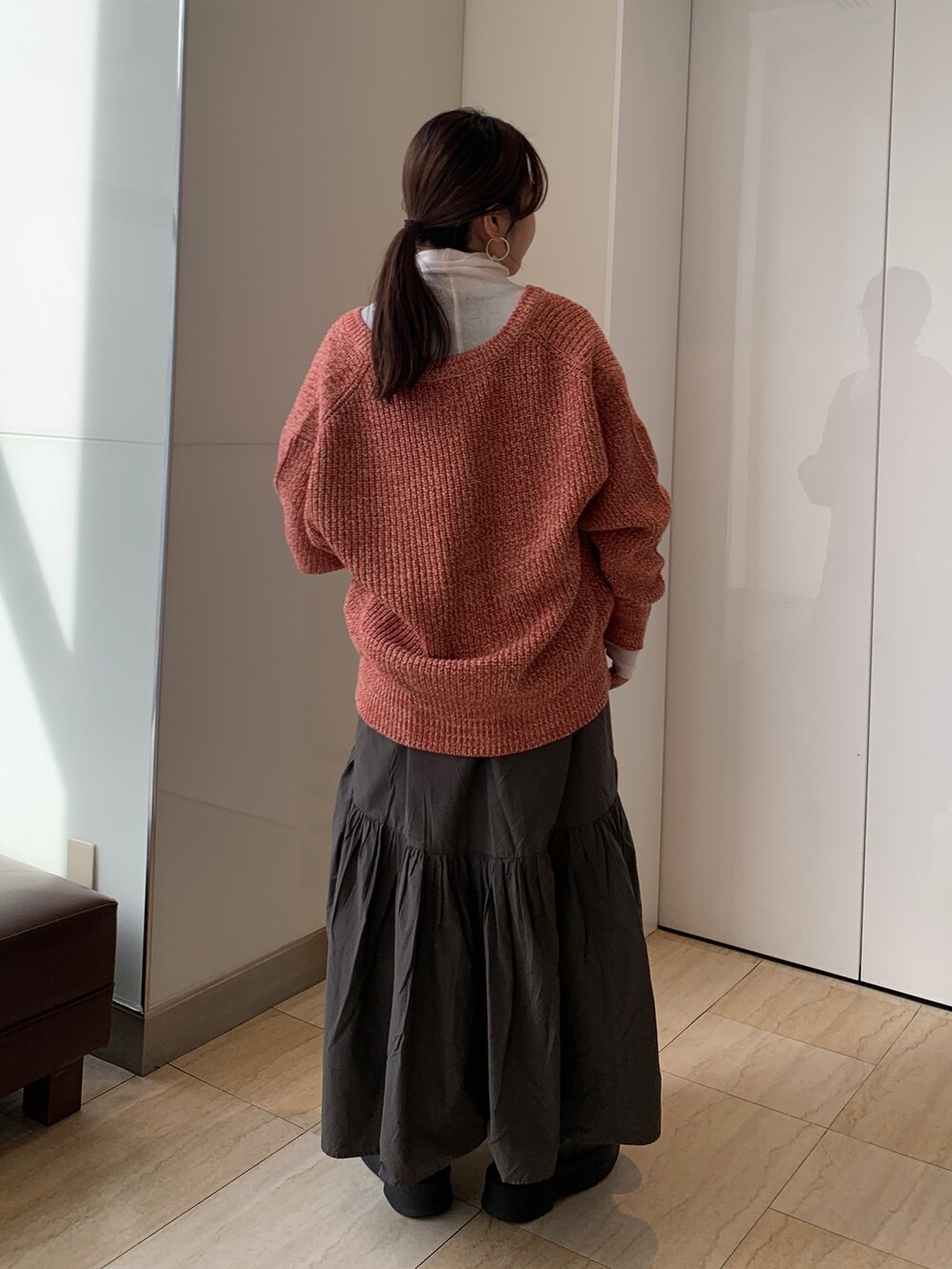 ピンク系のTシャツ/カットソー、オレンジ系のカーディガン/ボレロ、グレー系のスカートを着用したレディースの冬コーディネートの3枚目の写真