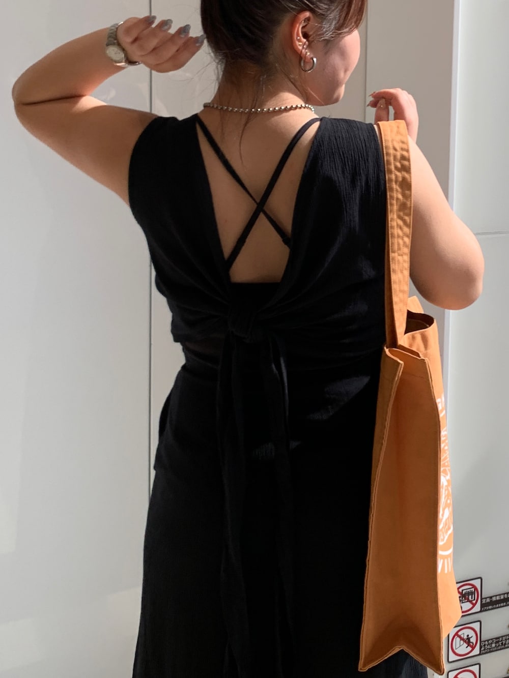 ブラック系のワンピース、オレンジ系のトートバッグを着用したレディースの春コーディネートの5枚目の写真