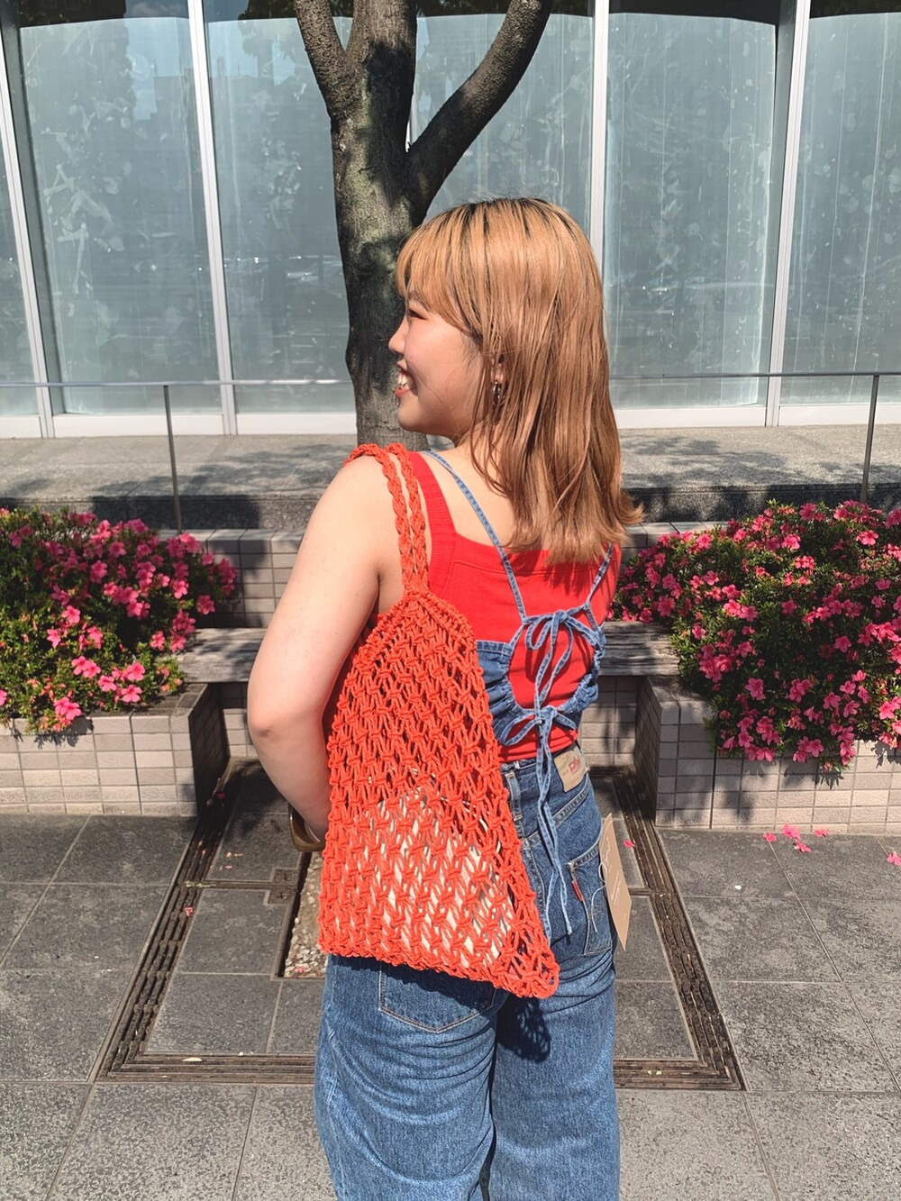 オレンジ系のタンクトップ、オレンジ系のハンドバッグを着用したレディースの夏コーディネートの3枚目の写真