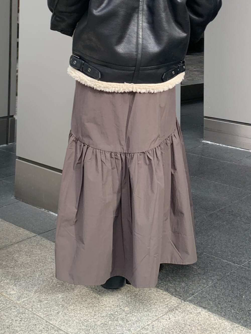 グレー系のスカート、ブラック系のブルゾン、ブルー系のニット/セーターを着用したレディースの冬コーディネートの7枚目の写真