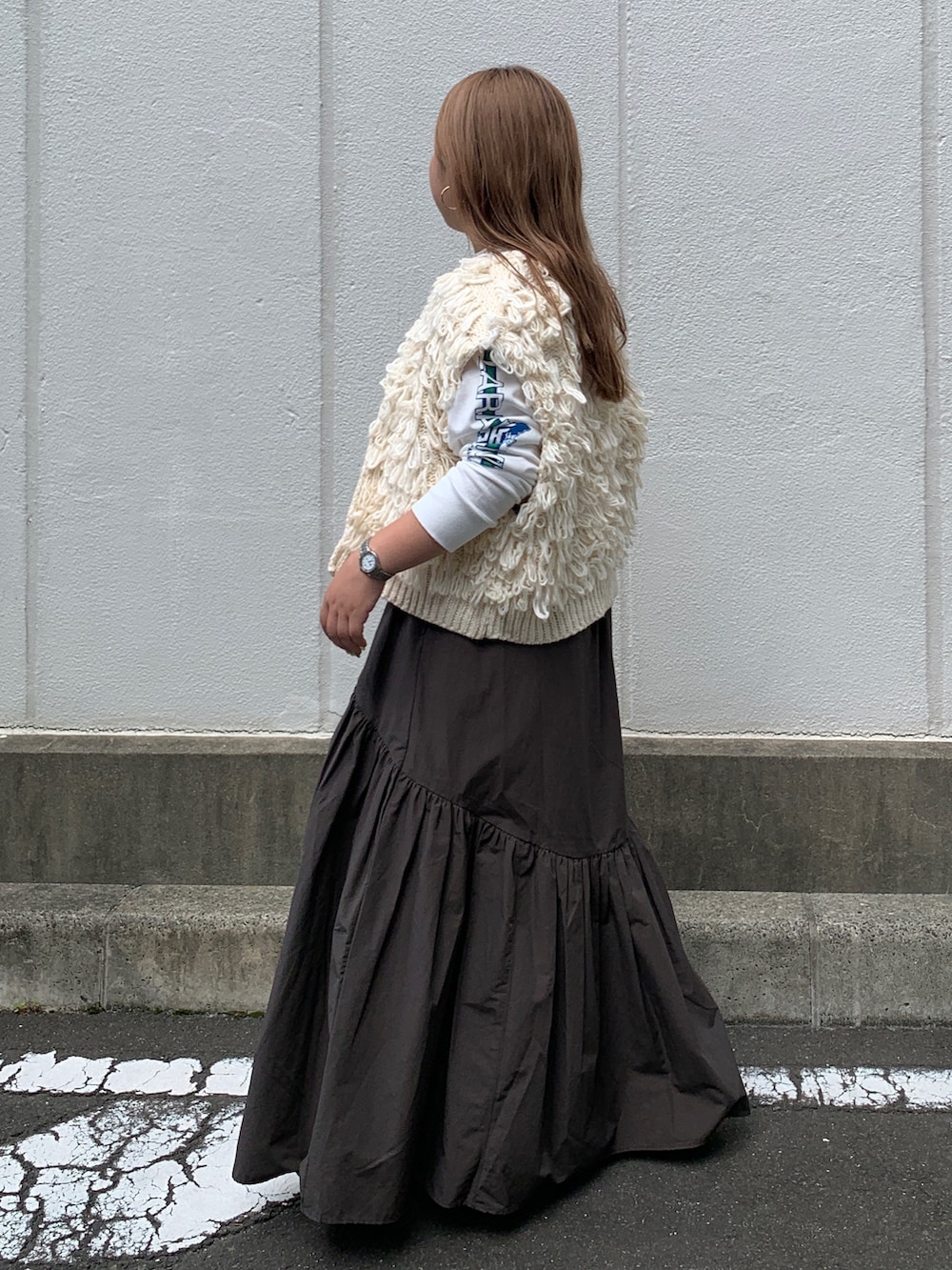 ホワイト系のTシャツ/カットソー、ホワイト系のベスト、グレー系のスカートを着用したレディースの秋コーディネートの2枚目の写真