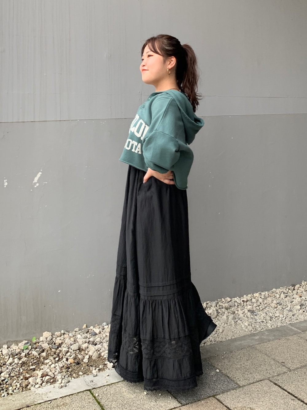 グリーン系のパーカー、ブラック系のスカートを着用したレディースの夏コーディネートの2枚目の写真