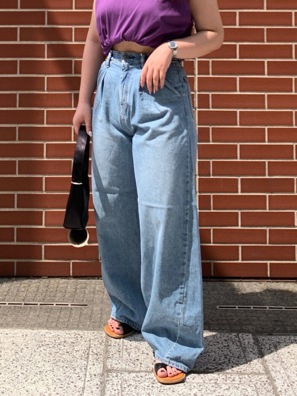 パープル系のタンクトップ、ブルー系のデニムパンツを着用したレディースの夏コーディネートの5枚目の写真