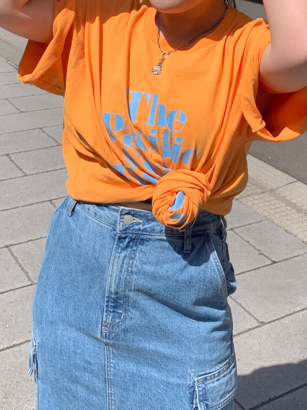 オレンジ系のTシャツ/カットソー、その他のショルダーバッグ、ブルー系のデニムスカートを着用したレディースの春コーディネートの4枚目の写真