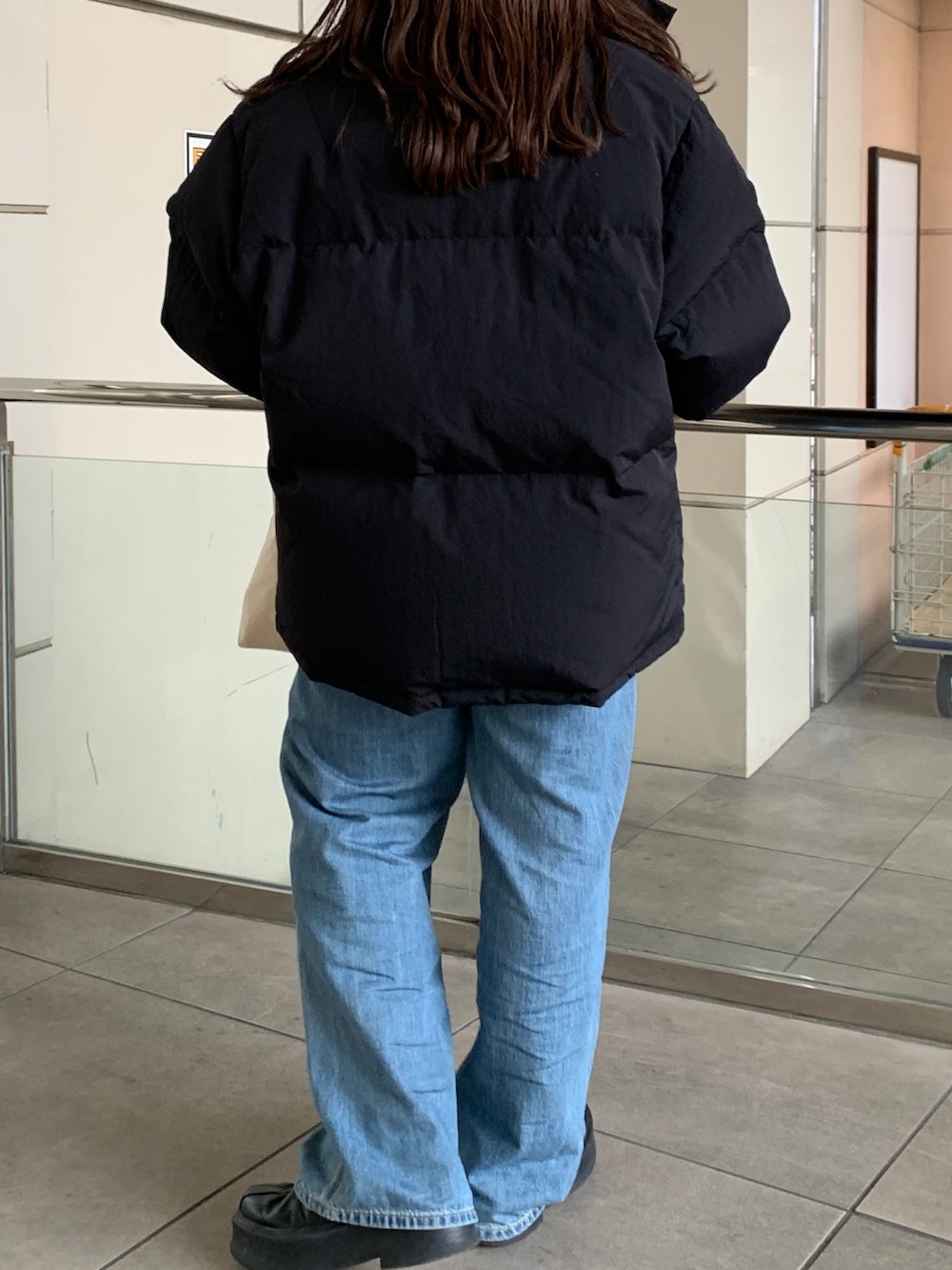 ブラック系のダウンジャケット/コート、グリーン系のニット/セーター、ブルー系のデニムパンツを着用したレディースの冬コーディネートの6枚目の写真