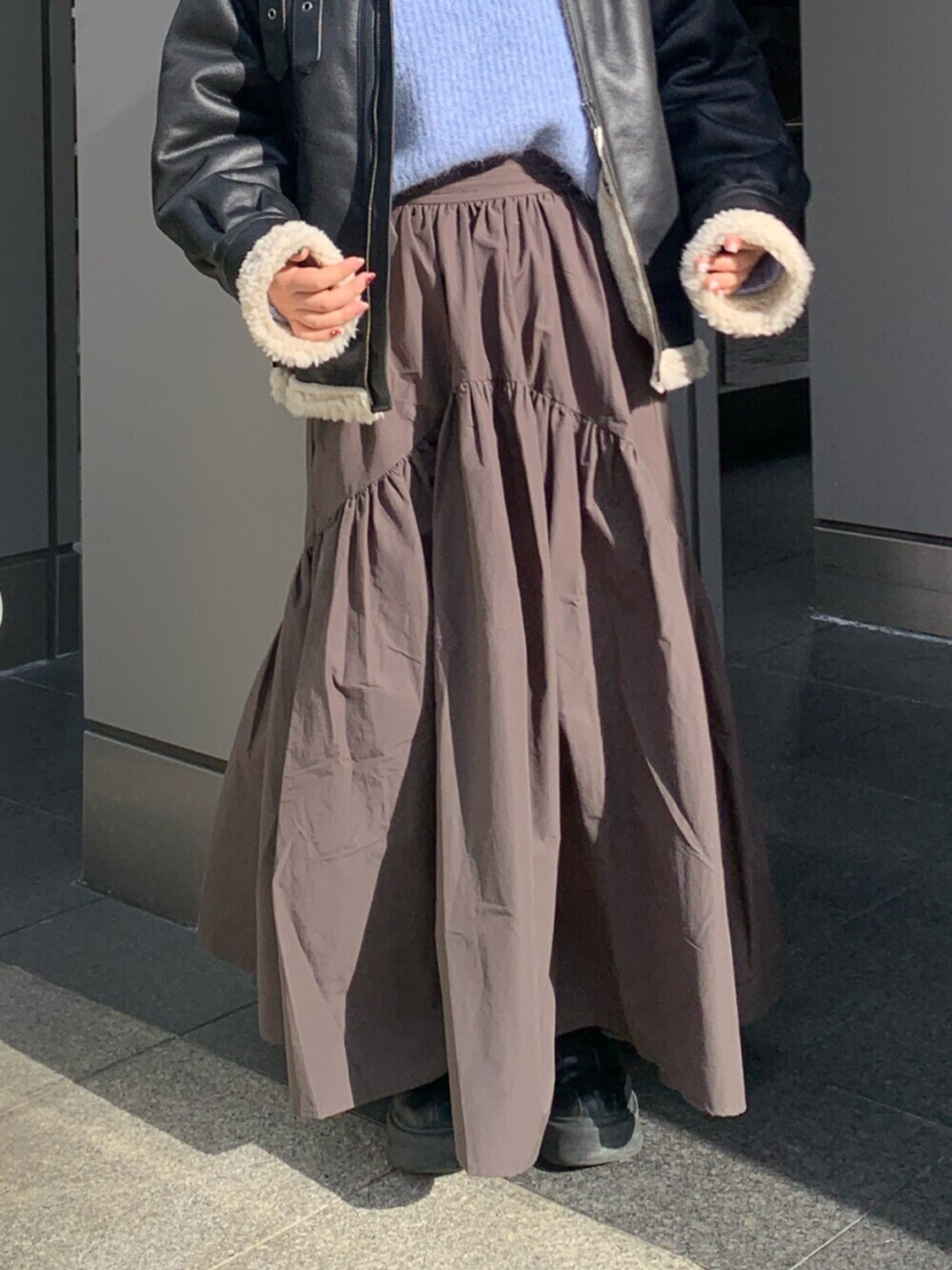 グレー系のスカート、ブラック系のブルゾン、ブルー系のニット/セーターを着用したレディースの冬コーディネートの5枚目の写真