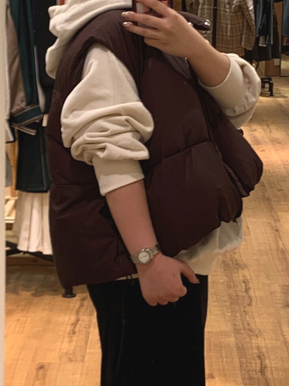 ブラウン系のダウンベスト、ホワイト系のパーカー、ブラック系のスカートを着用したレディースの秋コーディネートの5枚目の写真