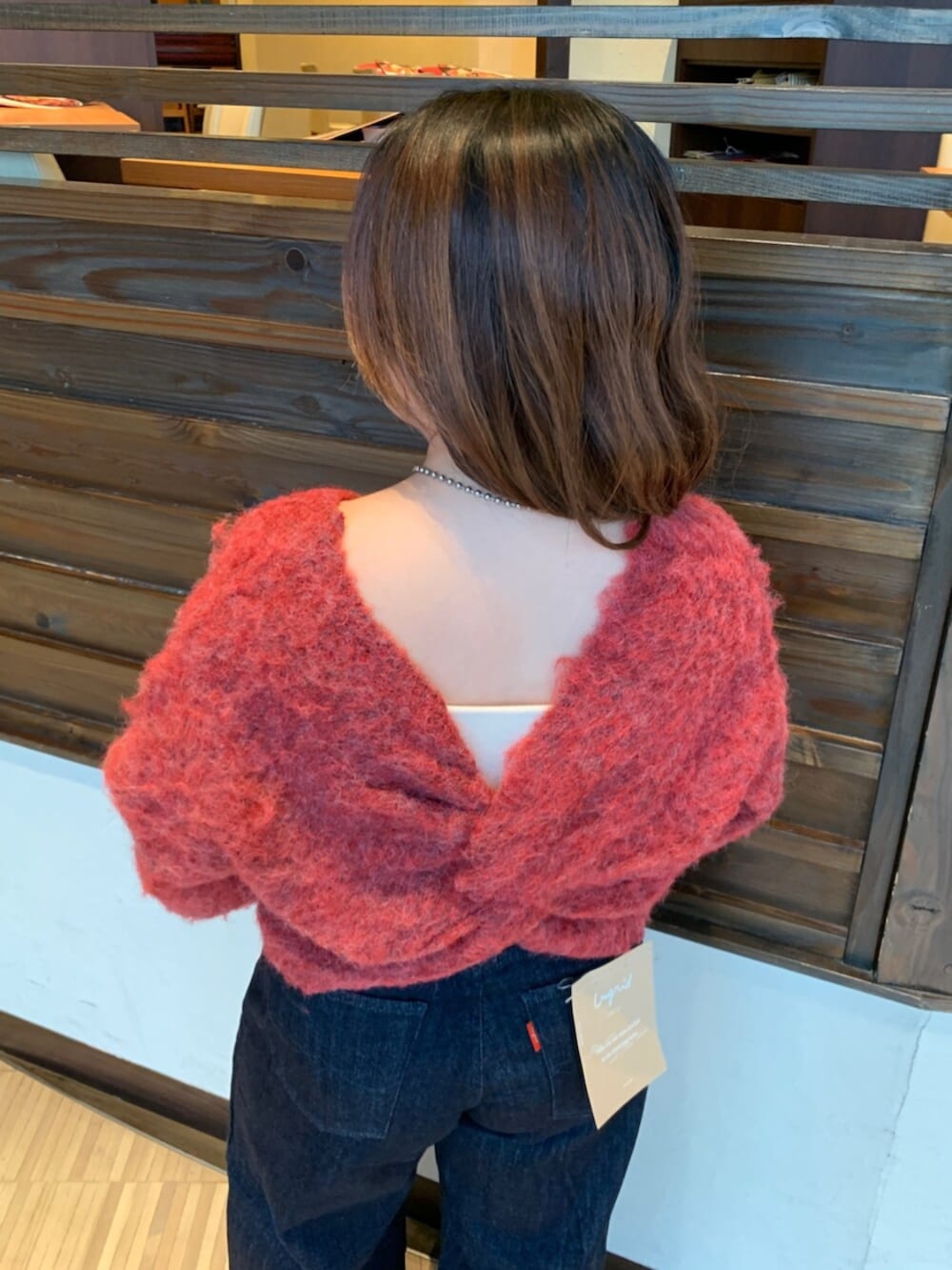 レッド系のニット/セーター、ブルー系のデニムパンツ、ブラウン系のハンドバッグを着用したレディースの秋コーディネートの8枚目の写真