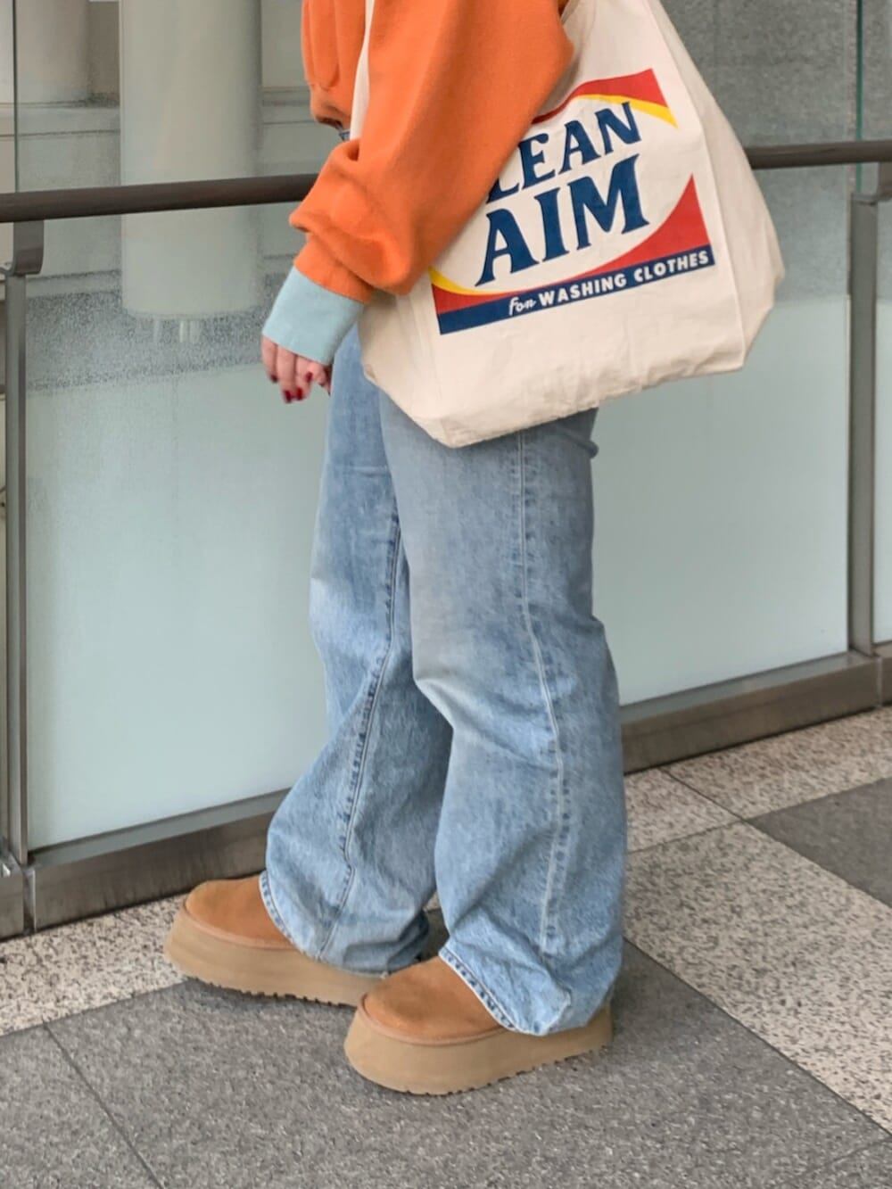 オレンジ系のニット/セーター、ブルー系のデニムパンツ、ホワイト系のトートバッグを着用したレディースの冬コーディネートの7枚目の写真