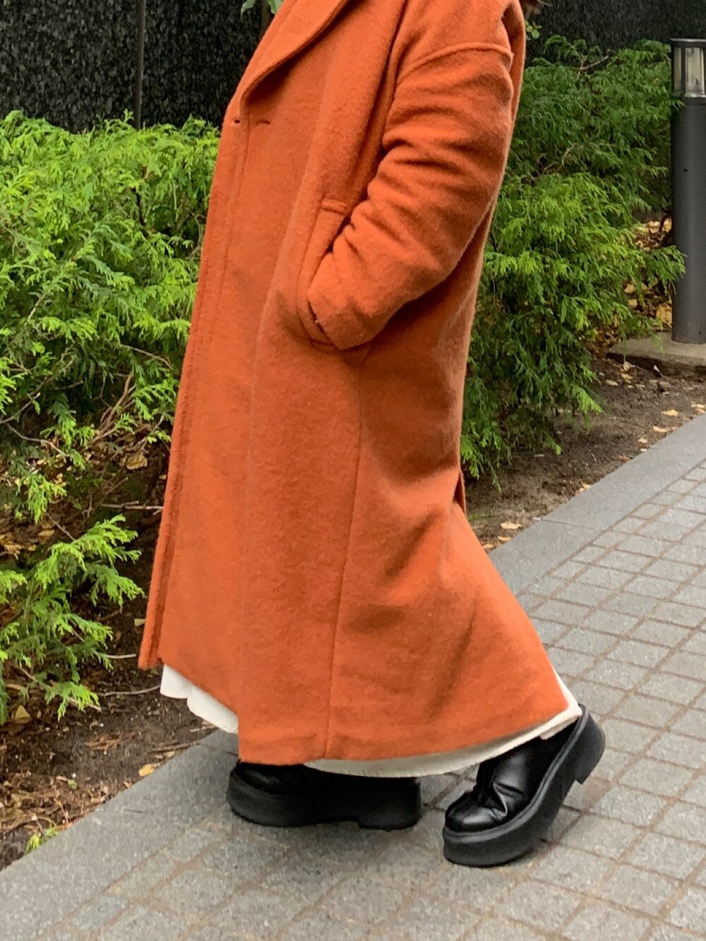 ブラウン系のニット/セーター、ブラック系のワンピース、オレンジ系のチェスターコートを着用したレディースの冬コーディネートの5枚目の写真