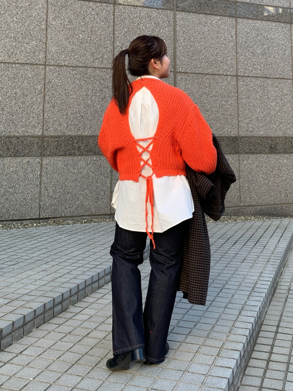 オレンジ系のニット/セーター、その他のチェスターコート、ブルー系のデニムパンツを着用したレディースの秋コーディネートの3枚目の写真