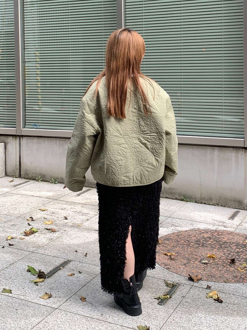 グリーン系のブルゾン、ホワイト系のTシャツ/カットソー、ブラック系のスカートを着用したレディースの秋コーディネートの3枚目の写真