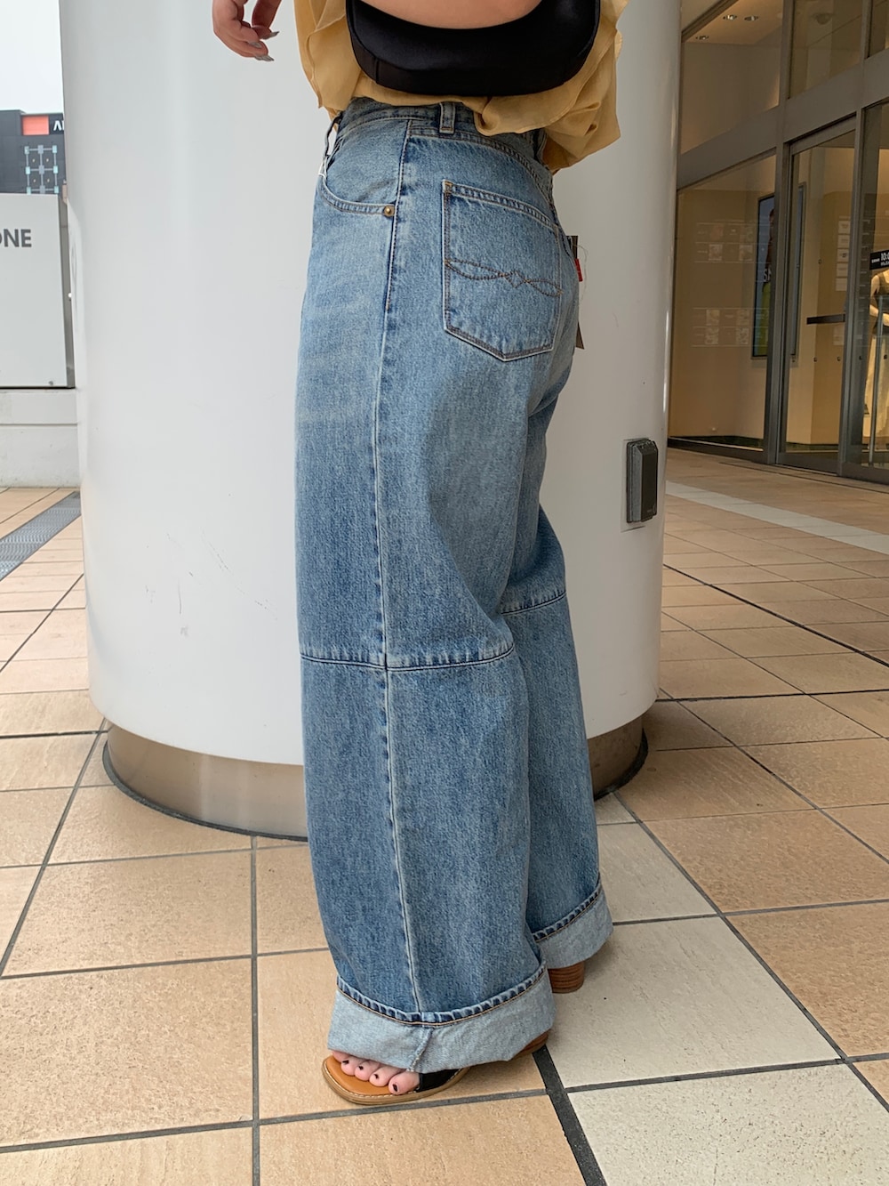 イエロー系のシャツ/ブラウス、ブルー系のデニムパンツを着用したレディースの夏コーディネートの6枚目の写真