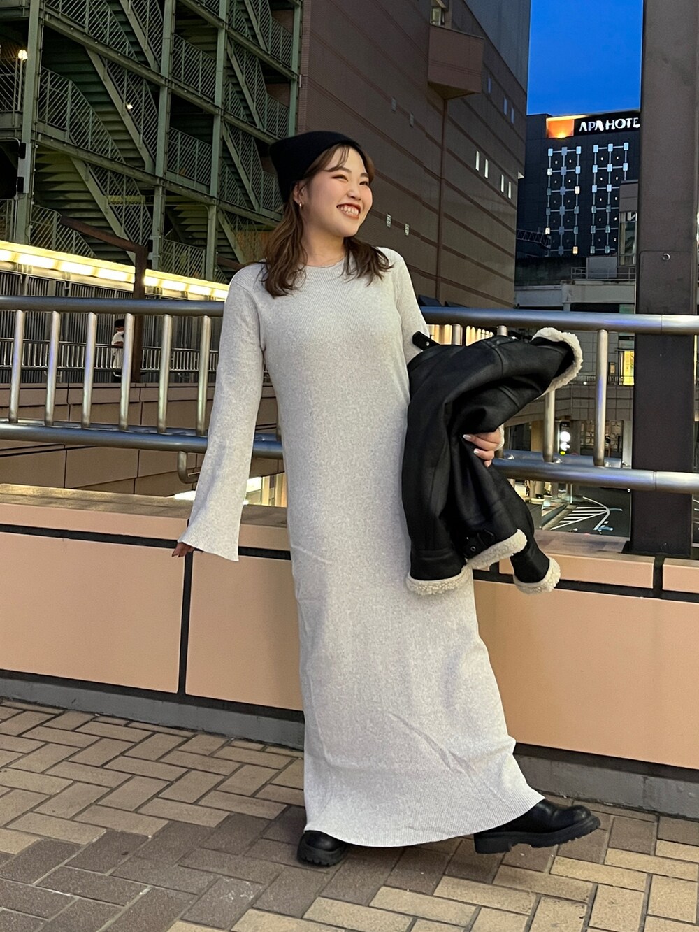 グレー系のワンピース、ブラック系のムートンコート、ブラック系のニットキャップ/ビーニーを着用したレディースの秋コーディネートの2枚目の写真