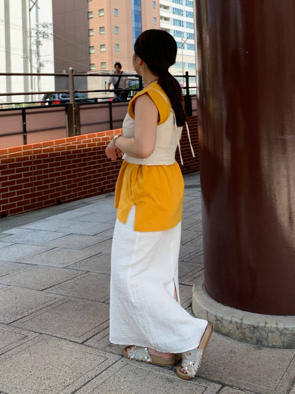 イエロー系のTシャツ/カットソー、ホワイト系のスカート、ホワイト系のキャミソールを着用したレディースの夏コーディネートの2枚目の写真