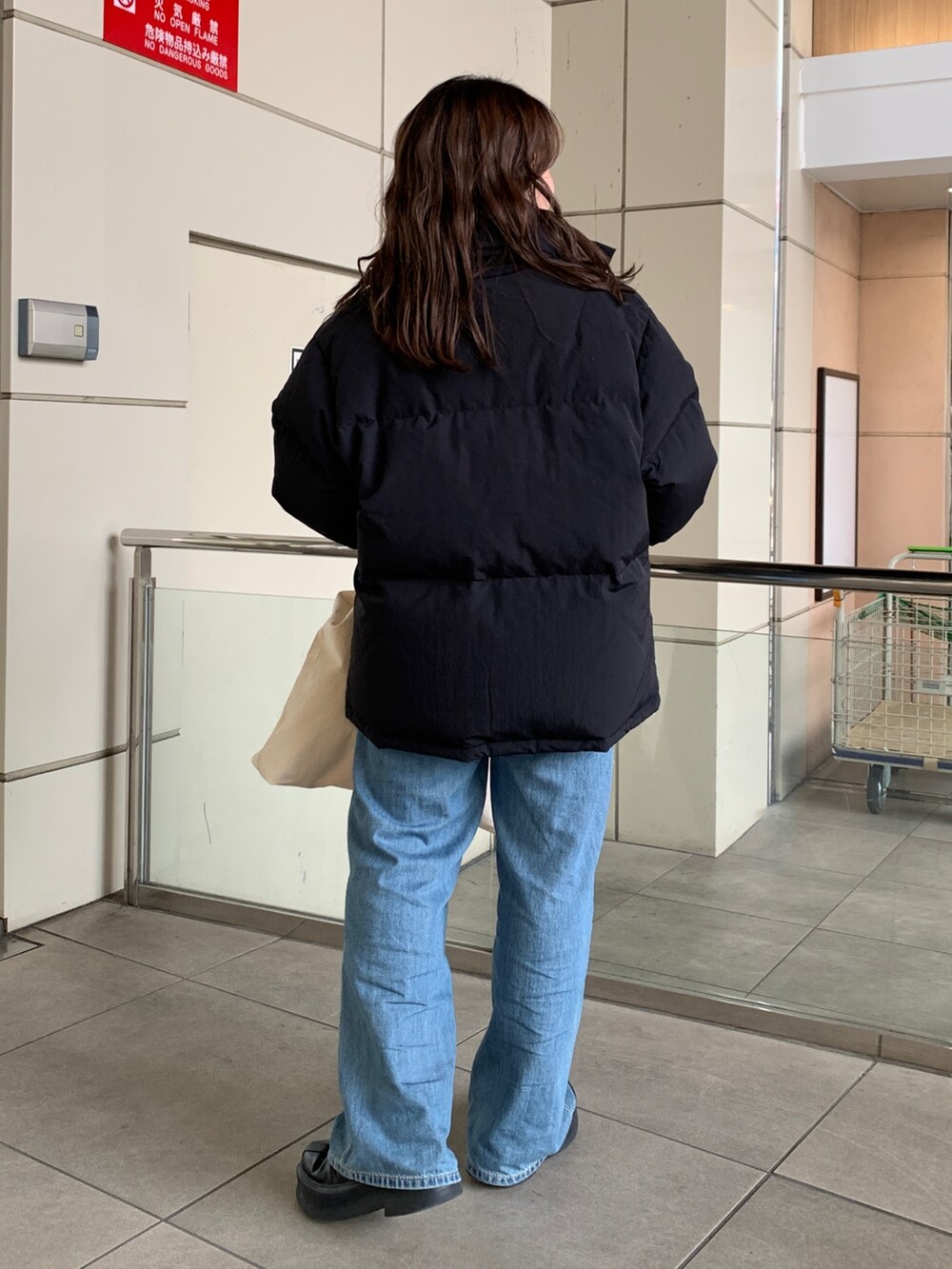 ブラック系のダウンジャケット/コート、グリーン系のニット/セーター、ブルー系のデニムパンツを着用したレディースの冬コーディネートの3枚目の写真