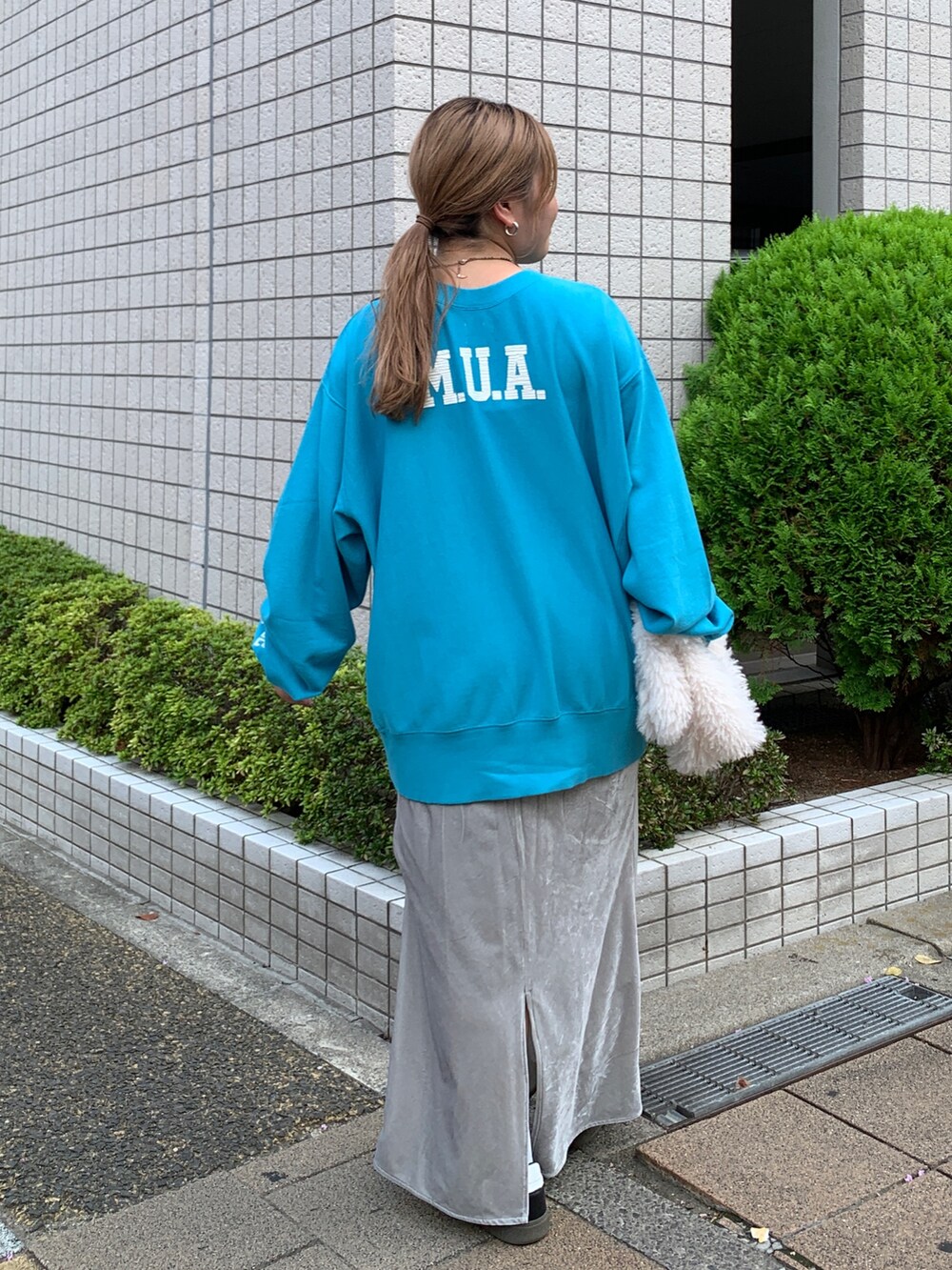 ブルー系のスウェット、ホワイト系のハンドバッグ、グレー系のスカートを着用したレディースの秋コーディネートの3枚目の写真