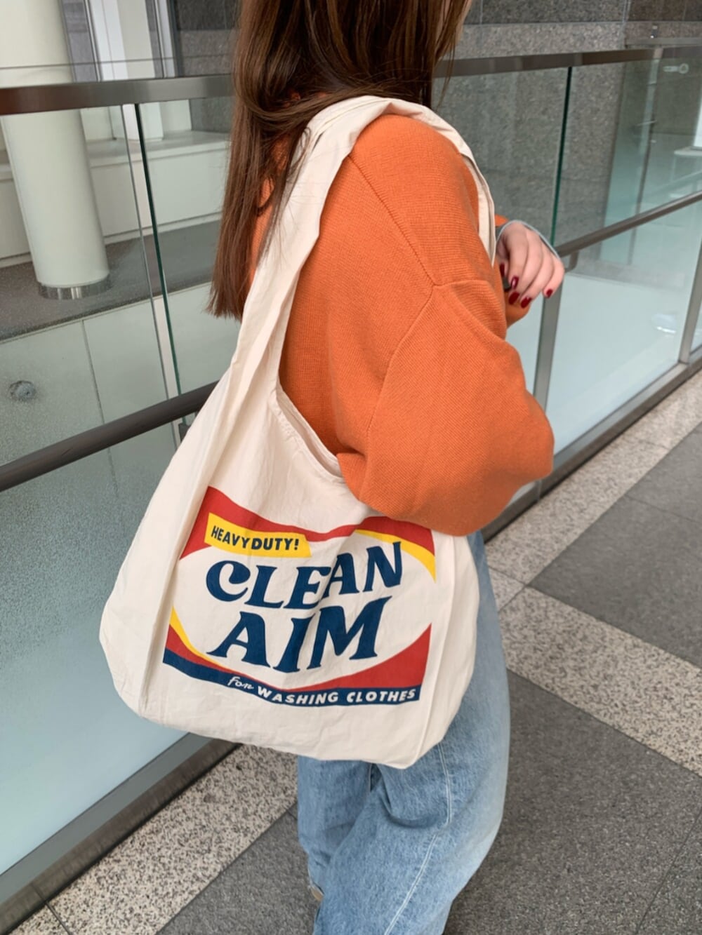 オレンジ系のニット/セーター、ブルー系のデニムパンツ、ホワイト系のトートバッグを着用したレディースの冬コーディネートの5枚目の写真