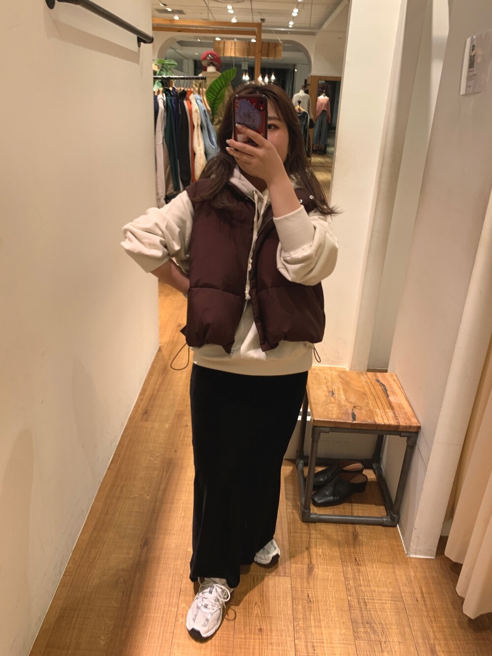 ブラウン系のダウンベスト、ホワイト系のパーカー、ブラック系のスカートを着用したレディースの秋コーディネートの7枚目の写真