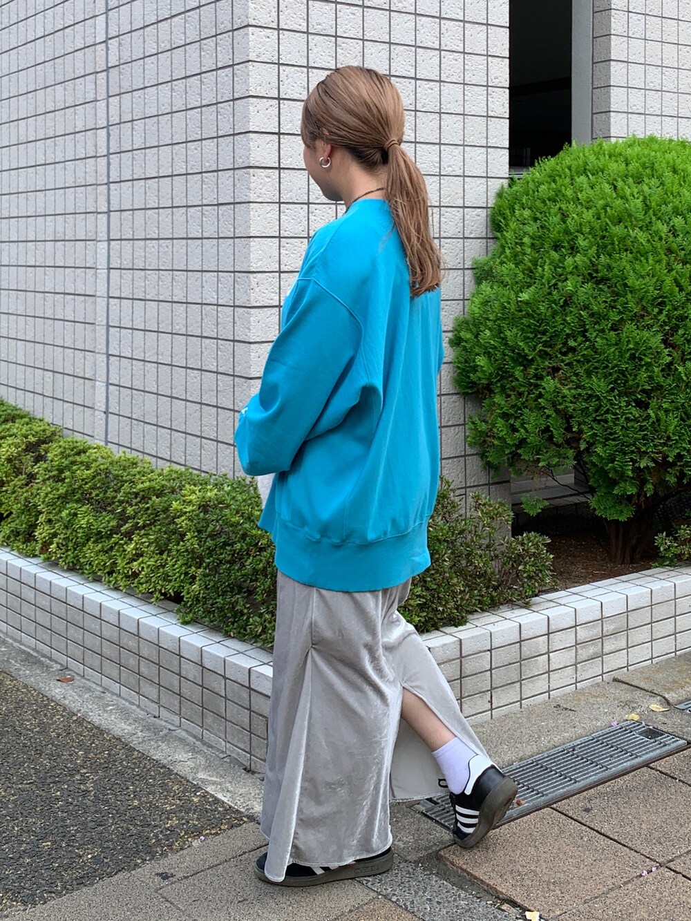 ブルー系のスウェット、ホワイト系のハンドバッグ、グレー系のスカートを着用したレディースの秋コーディネートの2枚目の写真